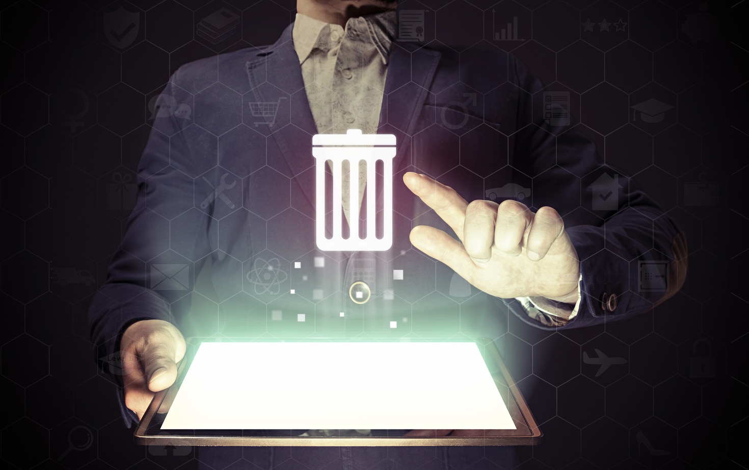 A business professional in a suit holds a tablet, its screen illuminated by a glowing trash can icon, symbolizing tech recycling in the digital age.