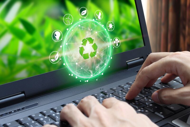 Hands typing on a laptop, referencing the 2021 Highlights with a recycling symbol surrounded by eco-related icons, set against a green, natural background.