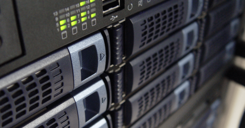 Close-up of several server racks with illuminated status lights, showcasing the NCS difference in data center hardware components.