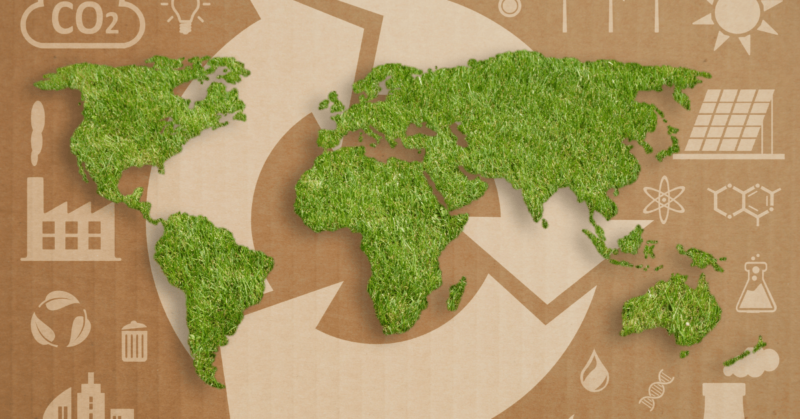 World map made of green grass over a cardboard background, adorned with white recycling symbols and eco-friendly icons, symbolizes how we can be doing good for the planet while doing well in our sustainable efforts.