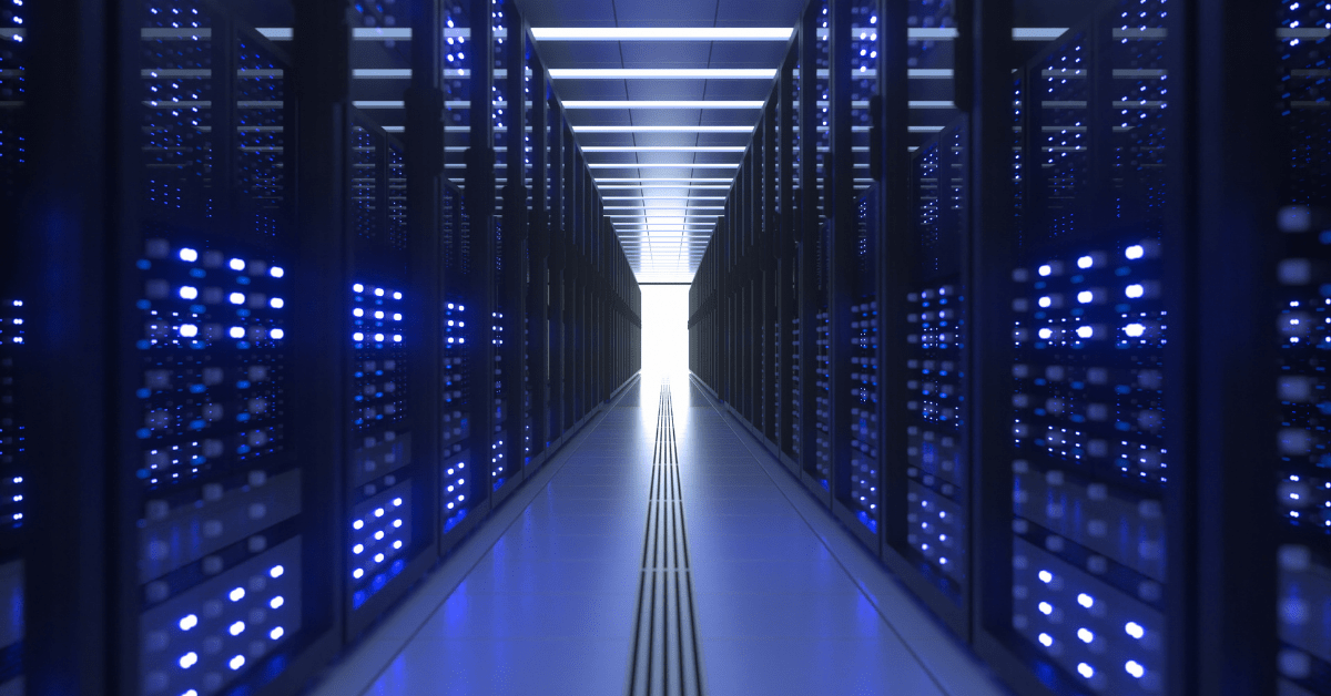 A brightly lit data center aisle lined with server racks on both sides, each filled with illuminated blue lights, stands as a testament to NCS's commitment to powering global technology success stories.