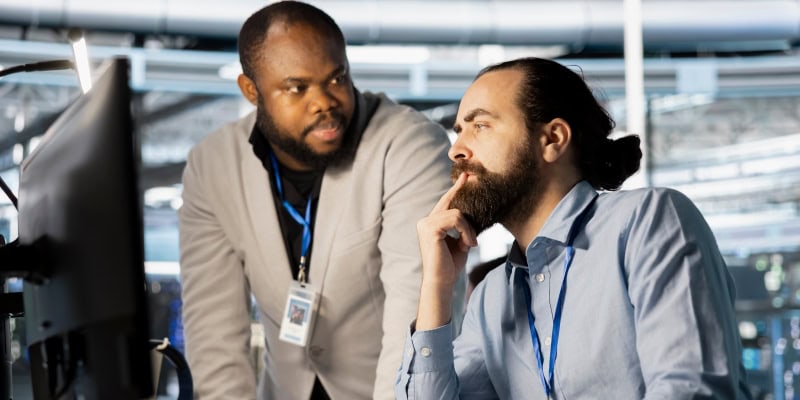Two professionals collaborating at computer in modern office setting