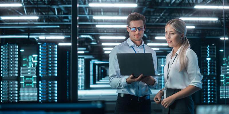 a male and female coworker reviewing performance results on a laptop in a data center a male and female coworker reviewing performance results on a laptop in a data center