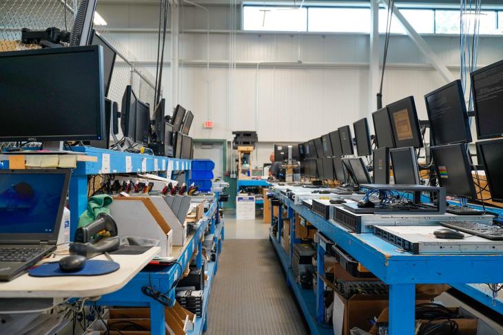 A room with multiple rows of desks lined with computer monitors and equipment in an environmentally friendly industrial setting