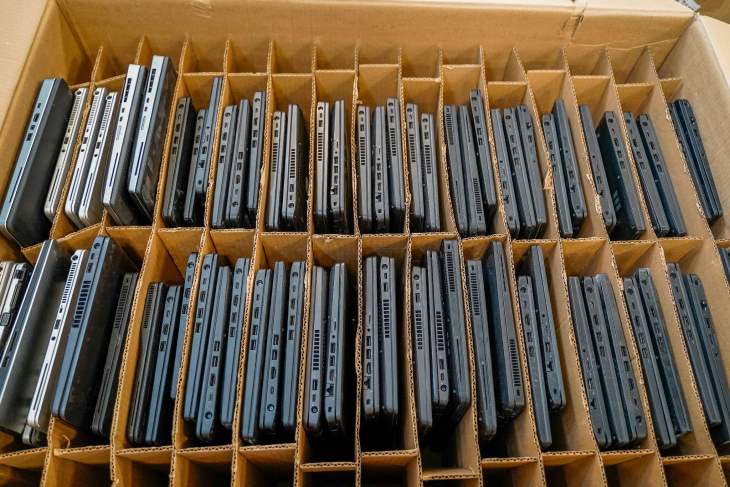 A box with multiple black laptops, neatly arranged in vertical rows and separated by cardboard dividers, reflects 2025 industry trends in ITAD.